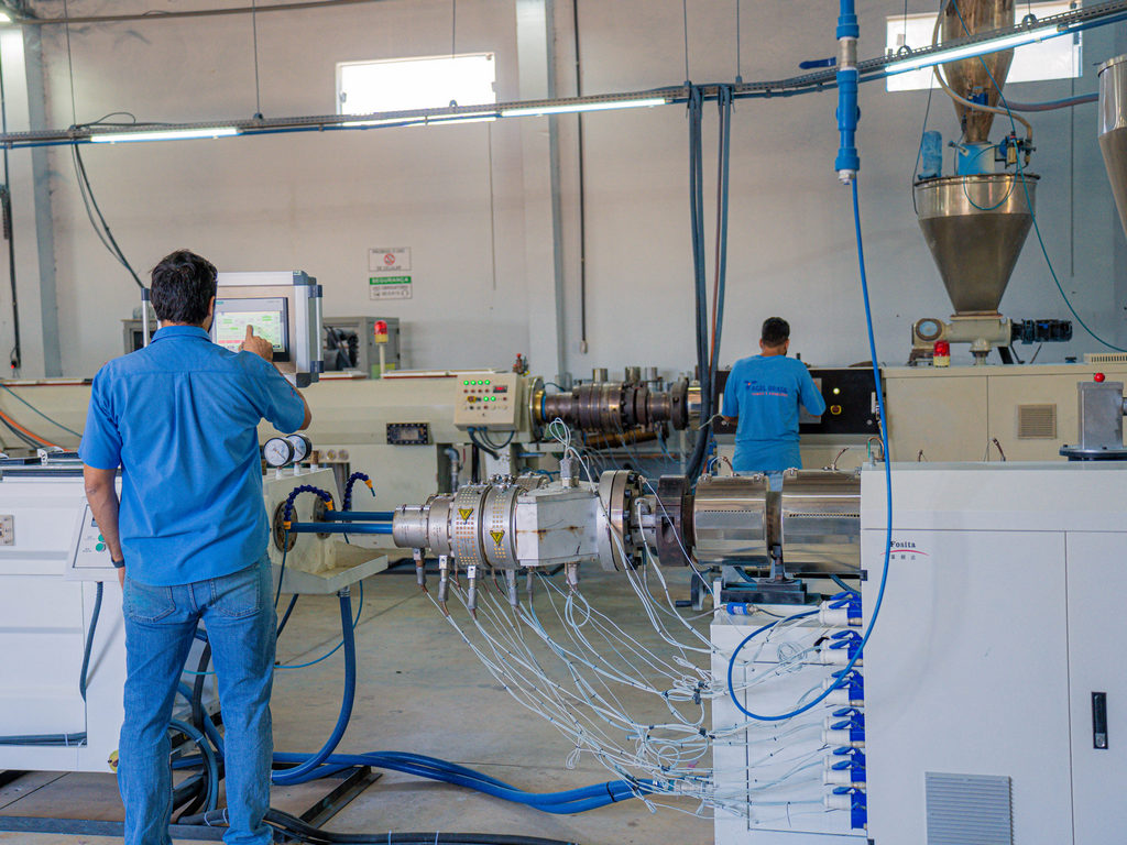 homem em pé configurando maquina na industria agel brasil